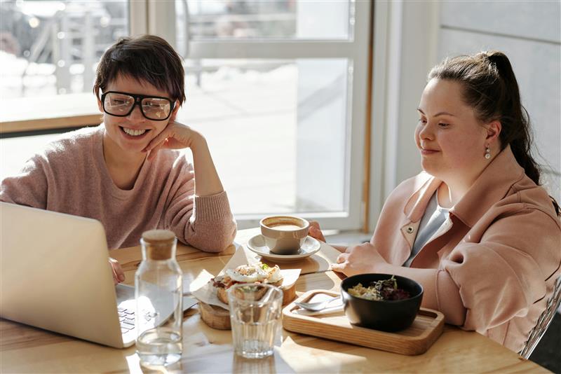 two women sitting at the breakfast table, looking at a computer
